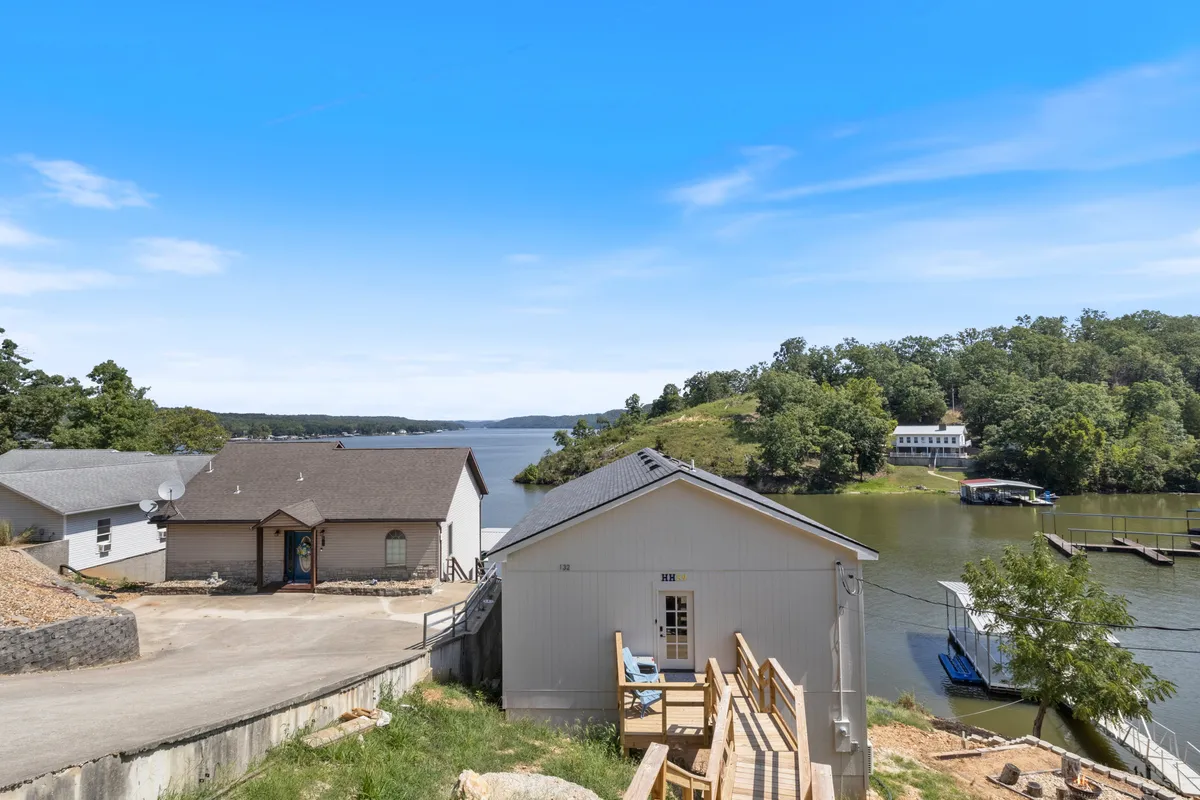 A picturesque lakeside view featuring the tranquil lake, a private dock extending into the water, and houses nestled along the shore. The scene is bathed in golden sunset light, inviting activities such as boating, fishing, and relaxing on the deck.