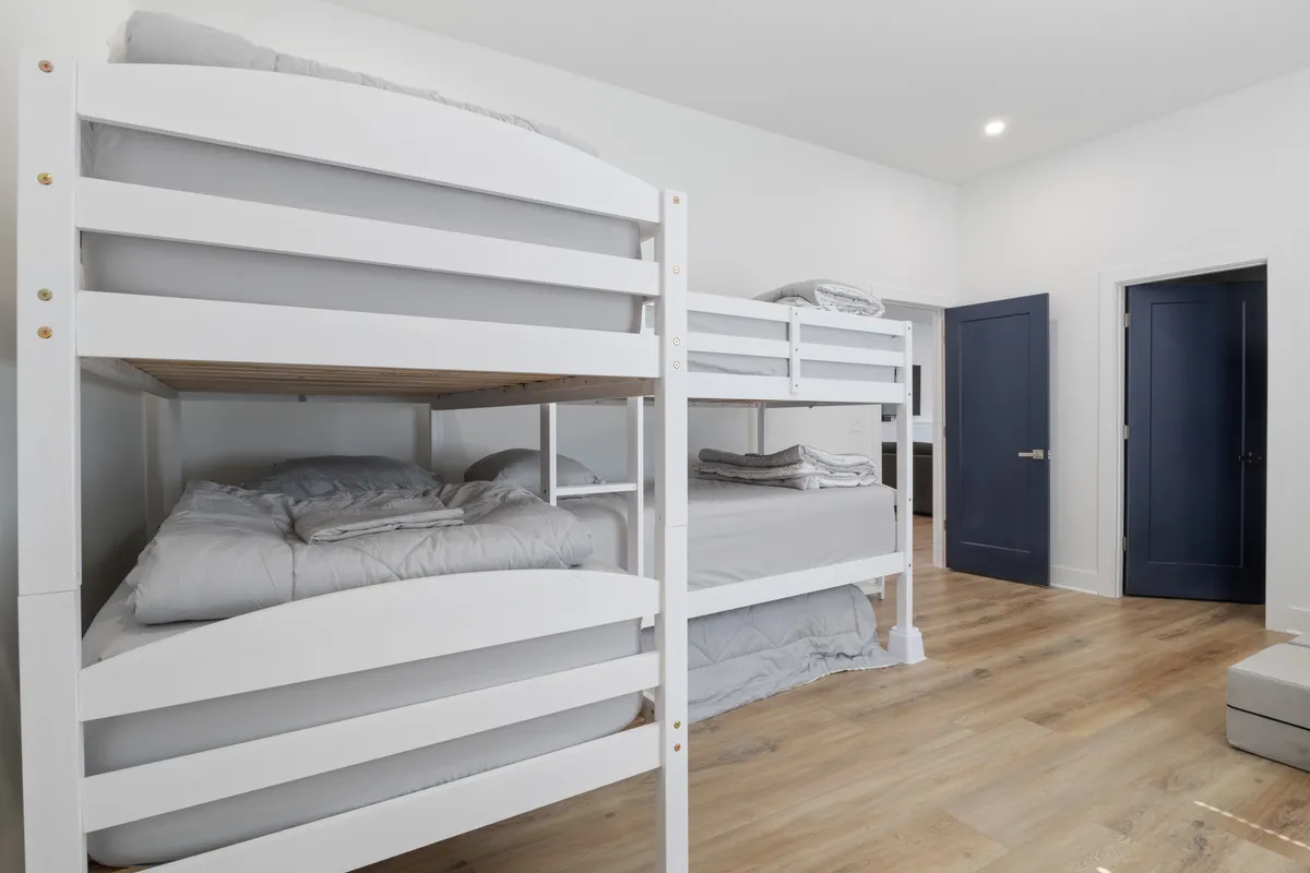 A cozy indoor bunk room with wooden floors and blue accents, featuring multiple bunk beds that create the perfect retreat for kids. The playful, inviting layout encourages bonding and playtime.